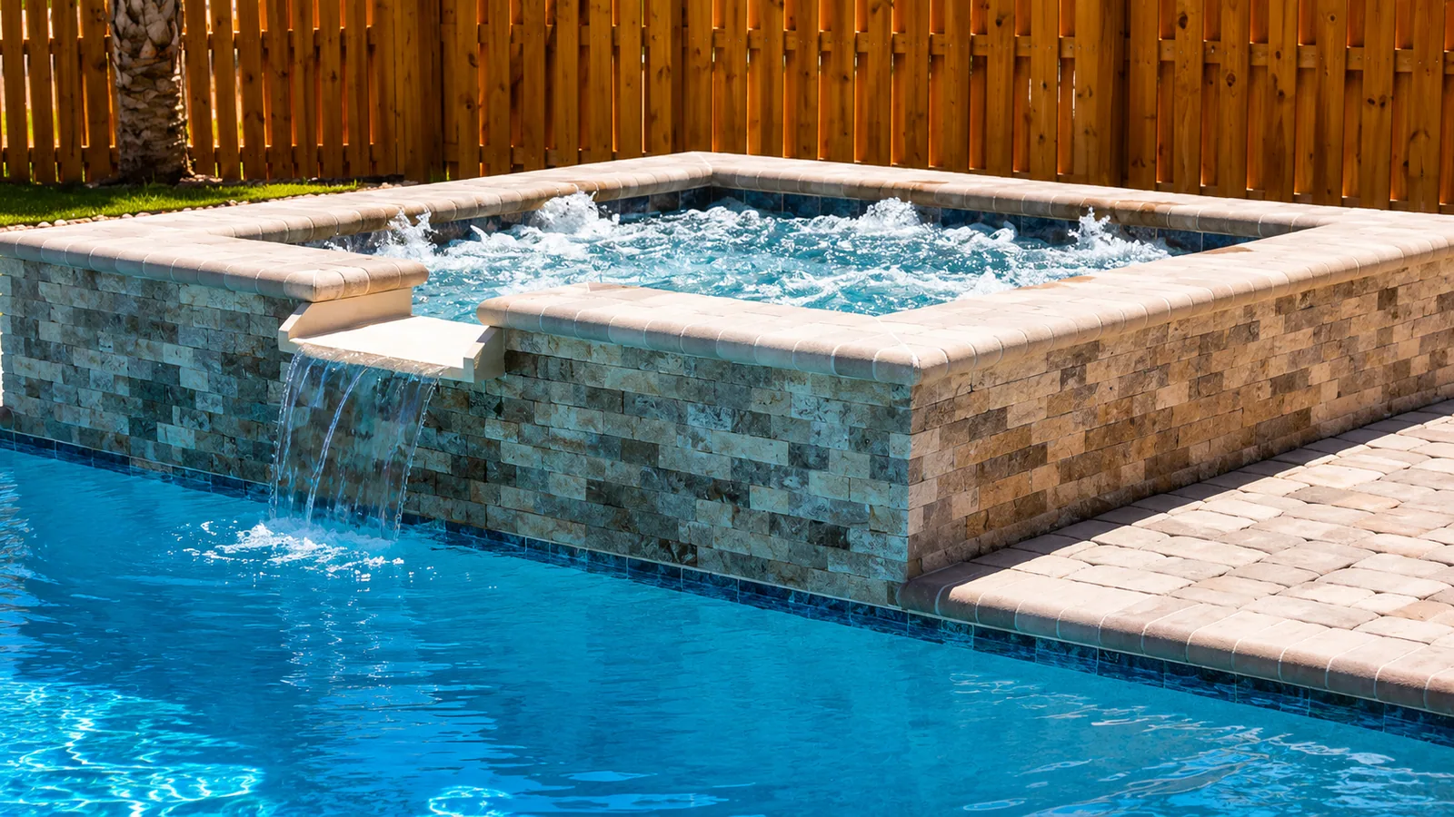 Raised spa with a spillway into a custom Neway pool