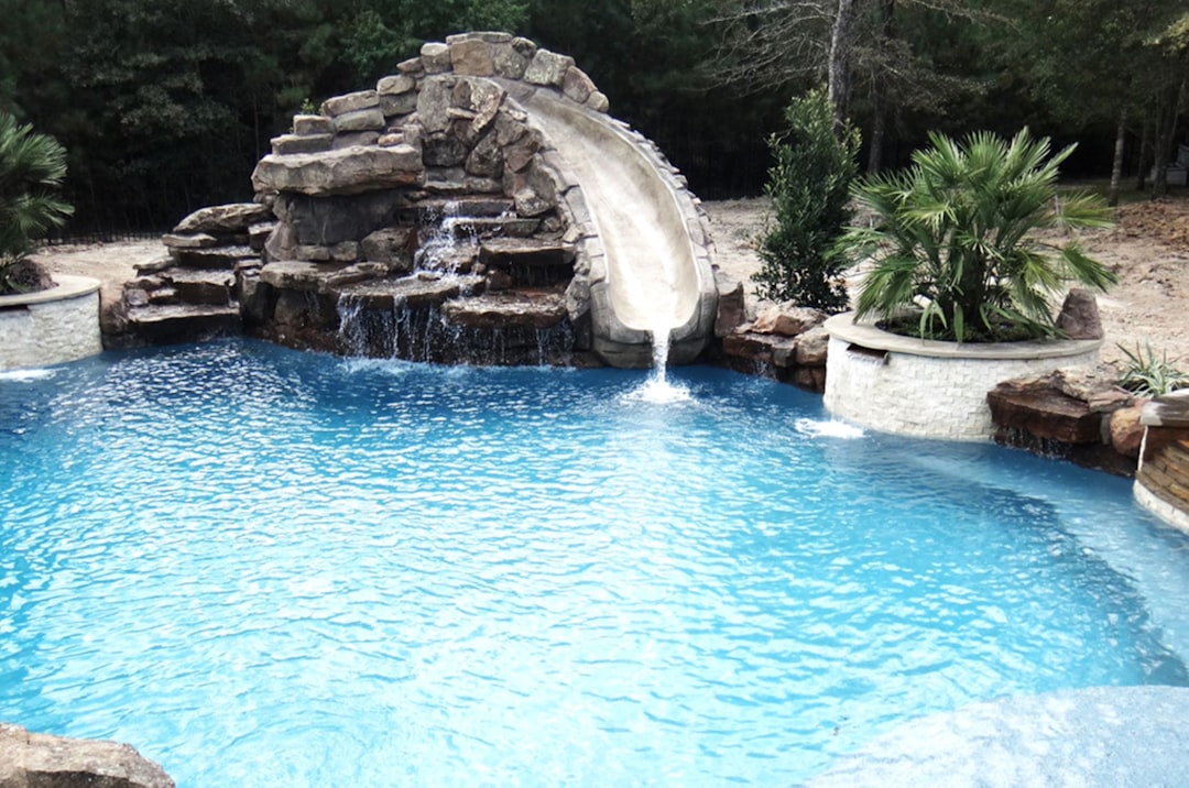 custom gunite pool with a unique water feature like a waterfall or grotto - custom swimming pool builders